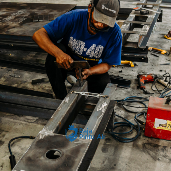Salah satu langkah perakitan pintu air mulailah dari frame: las besi siku galvanis, lalu pasang guide rail paralel 